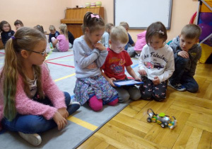 w grupie dzieci chłopiec steruje tabletem pojazd