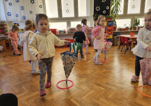 przedszkolaki tańczą z parasolkami idąc wokół nich