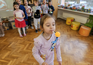 zabawa sprawnościowa - dziewczynka niesie małą piłeczkę na łyżce niesionej w ustach
