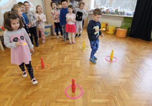 zabawa sprawnościowa - dzieci niosą małą piłeczkę na łyżce niesionej w ręce i idą między kręglami slalomem