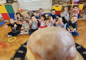 przedszkolaki wyciągają ręce w stronę pączka