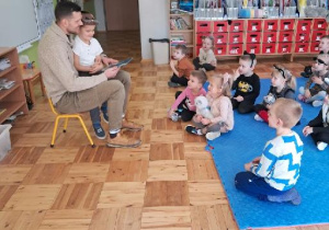 tata trzyma na kolanach córkę i rozmawia z dziećmi o bajce