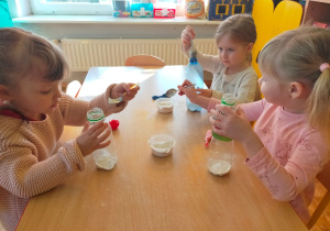 dziewczynki wsypują mąkę łyżkami do butelki