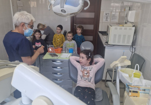 pani stomatolog rozmawia z dziewczynkom, która siedzi na fotelu