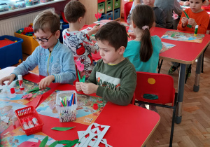 dzieci przy stolikach wykonują tulipany z gotowych elementów
