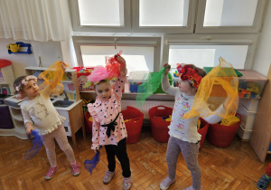 dziewczynki w wiankach tańczą z kolorowymi chustkami