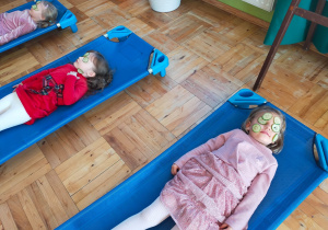 dziewczynki leżą na leżakach i maseczkami z zielonego ogórka