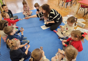 prowadząca rozdaje lusterka dzieciom siedzącym w kółeczku