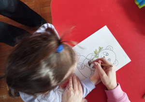 dziewczynka uczy się kolorować obrazek pandy