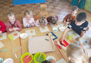 przedszkolaki ozdabiają swoje ciasteczko kolorowymi lukrami