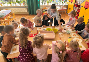 przedszkolaki ozdabiają swoje ciasteczko kolorowymi lukrami