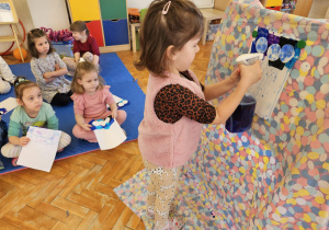 dziewczynka psika wodą na kartkę aby uzyskać kolorowy deszcz