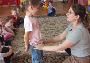 prowadząca trzyma dziewczynkę za biodra