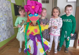 przedszkolaki z Marzannąw różowych kwiatach na głowie i zielonymi warkoczami w sali