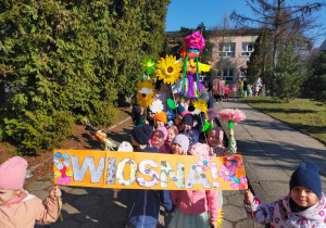 przedszkolaki ustawione w korowodzie przed budynkiem przedszkola z rekwizytami