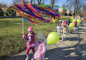 przedszkolaki w wiosennymi korowodzie na ulicach miasta z dużym gaikiem i balonami