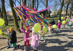 przedszkolaki w wiosennymi korowodzie na ulicach miasta z dużym gaikiem i balonami