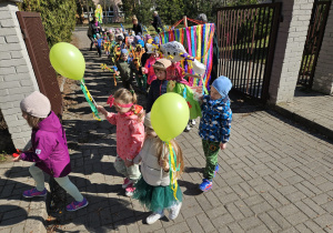 dzieci wychodzą z terenu przedszkola na ulice miasta w wiosennym korowodzie
