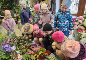 dzieci w kwiaciarni oglądają wczesne kwiaty w doniczkach