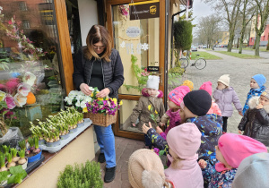 pani kwiaciarka wręcza dzieciom po sztucznym kwiatku