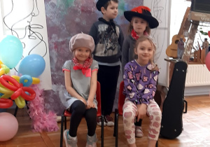 przedszkolaki w strojach artystów pozują do zdjęcia na tle płótna i obrazów