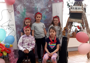 przedszkolaki w strojach artystów pozują do zdjęcia na tle płótna i obrazów