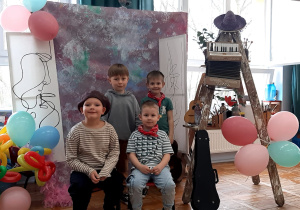 przedszkolaki w strojach artystów pozują do zdjęcia na tle płótna i obrazów