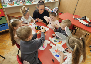 przedszkolaki w strojach zajęcy kolorują mazakami
