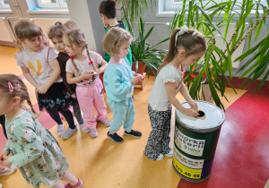 przedszkolaki wrzucają baterie do pojemnika w kształcie baterii stojącego w przedszkolnej szatni