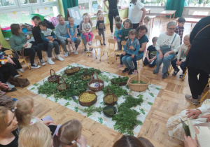 dorośli z dziećmi siadają na krzesełkach wokół zgromadzonych wziół