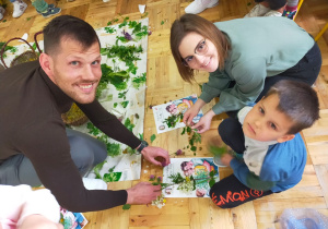 rodzice z dziećmi układają bukiety ziołowe