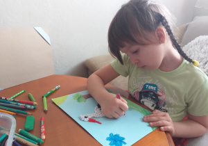 dziecko robi pracę plastyczną - bociana na łące
