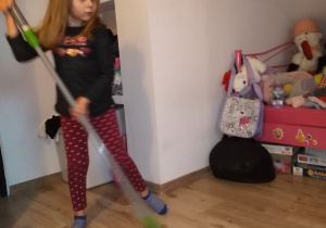 dziewczynka myje mopem podłogę w swoim pokoju