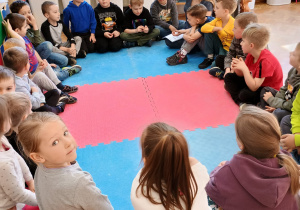 dzieci rozmawiaja z prowadzącą siedząc w kole