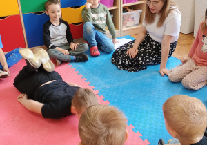 przedszkolaki siedzą w kole z panią Kasią a chłopiec w środku pokazuje ćwiczenie
