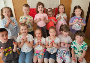 grupa dzieci pozuje do zdjęcia z miniaturowymi flagami Polski