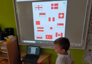 dzieci szukają flgi Polski na tablicy multimedialnej