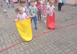 przedszkolaki skaczą w workach na tarasie przedszkolnym