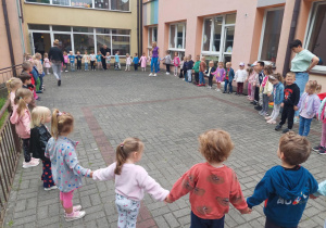 przedszkolaki podczas zabawy na tarasie przedszkolnym stoją w wielkim kole