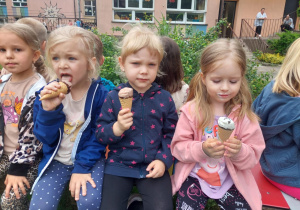 dzieci jedzą lody siedząc w ogrodzie