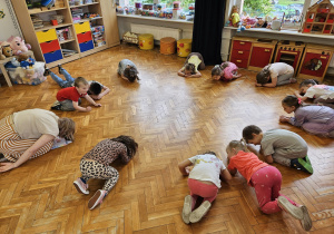przedszkolaki ćwiczą - klęczą w siadzie skulnym
