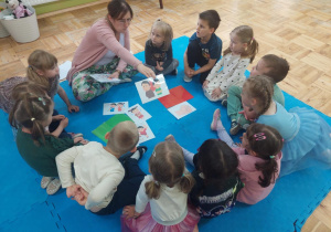 pani Kasia pokazuje dzieciom obrazki a dzieci określają emocje jakie pokazują dzieci na obrazku