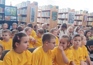 dzieci siedzą na krzesełkach w bibliotece