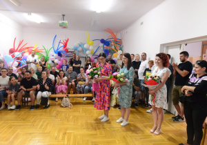 mamy stoją z kwiatami od rodziców dla nauczycielek i pani dyrektor