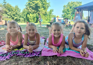dziewczynki w kostiumach leżą na brzuchu na ręcznikach plażowych w ogrodzie przedszkolnym