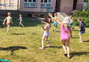 dziewczynki w kostiumach siedzą na ręcznikach plażowych w ogrodzie przedszkolnym