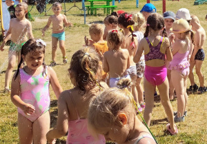 dzieci biegają pod kroplami deszczu w ogrodzie przedszkolnym