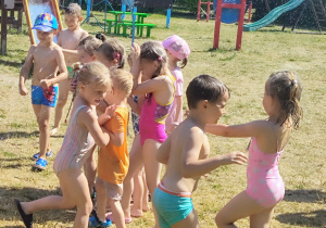 dzieci biegają pod kroplami deszczu w ogrodzie przedszkolnym