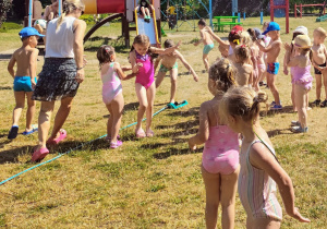 dzieci biegają pod kroplami deszczu w ogrodzie przedszkolnym
