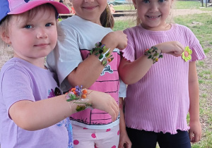 dziewczynki pokazują swoje bransoletki z kwiatów z ogrodu przedszkolnego